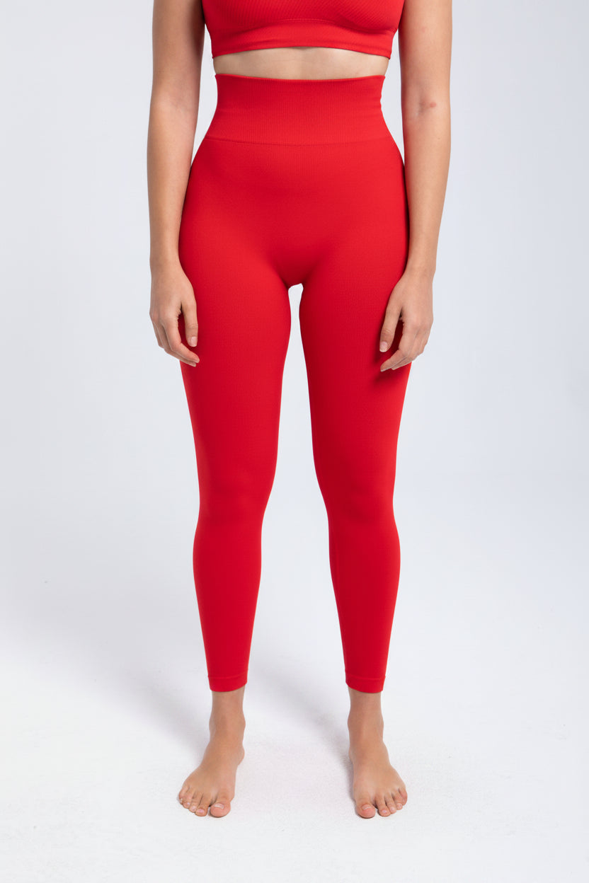 Person wearing red leggings and a matching top on a white background